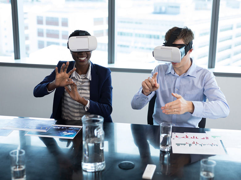 Smiling woman and man using virtual reality headsets in office.