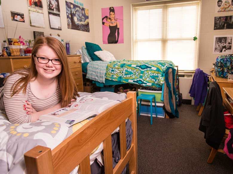 A Penn State Behrend female student studies in her tastefully decorated dorm room.