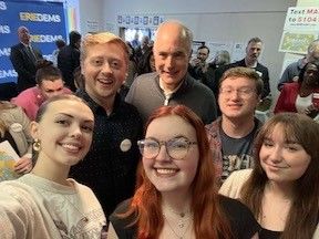 A group of students stand with a male politician
